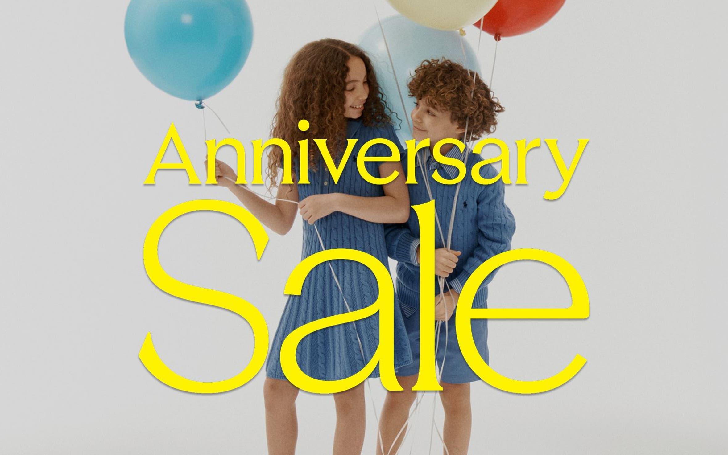 Girl and boy holding ballons with Anniversary Sale graphic