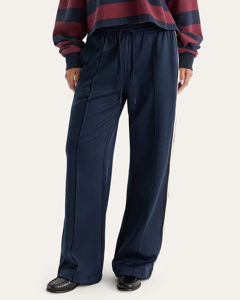 A woman wearing a pair of navy blue track pants.