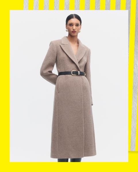 A woman in a taupe wool wrap coat with a brown leather belt.