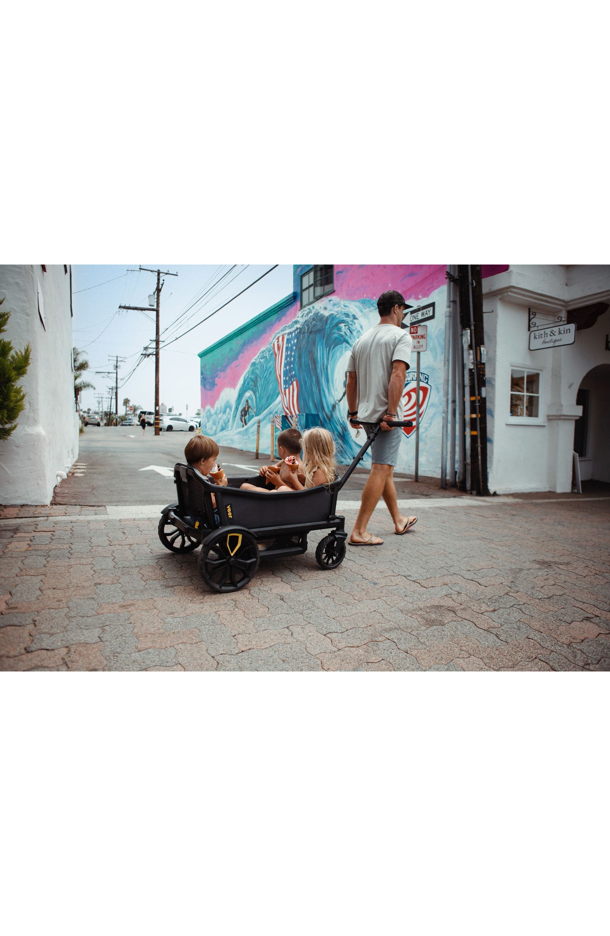 Man pulling three children in a Veer wagon. 