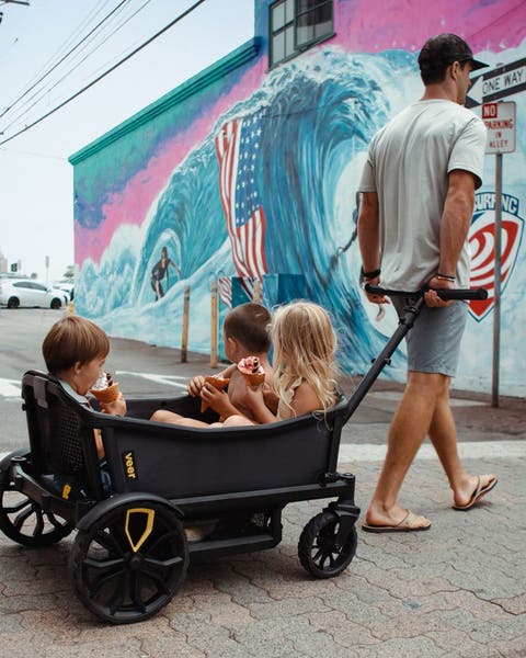 Man pulling three children in a Veer wagon.
