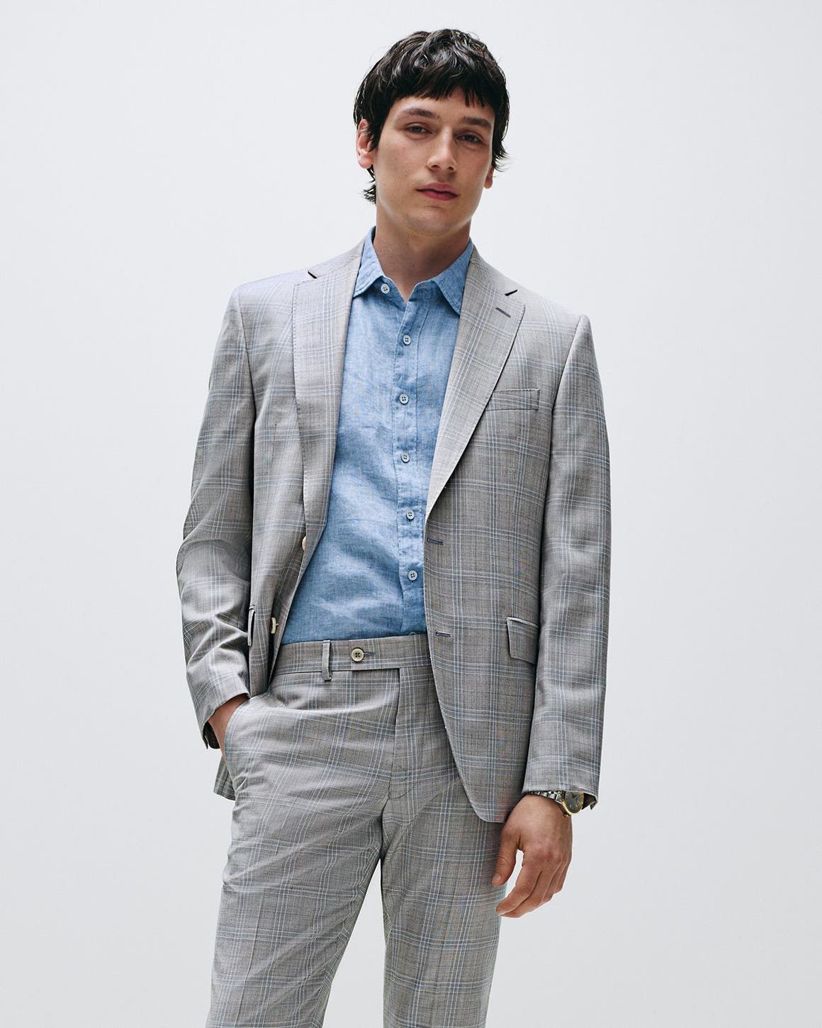 Man wearing a grey plaid suit and blue button-down.