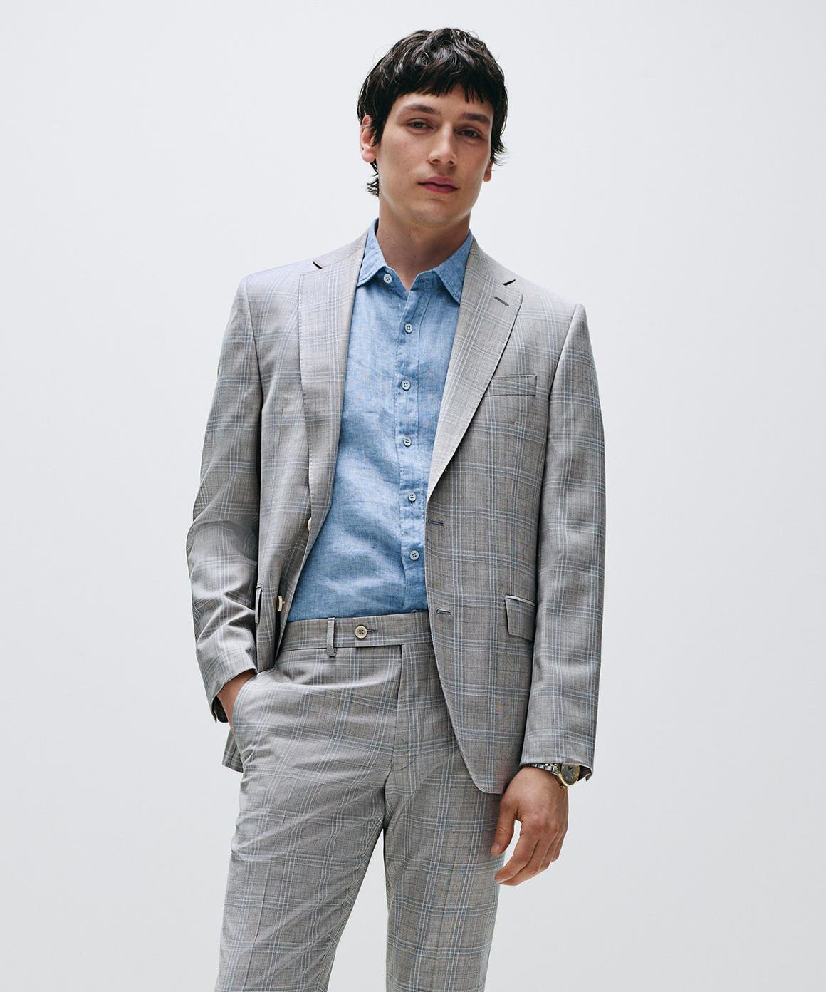 Man wearing a grey plaid suit and blue button-down.