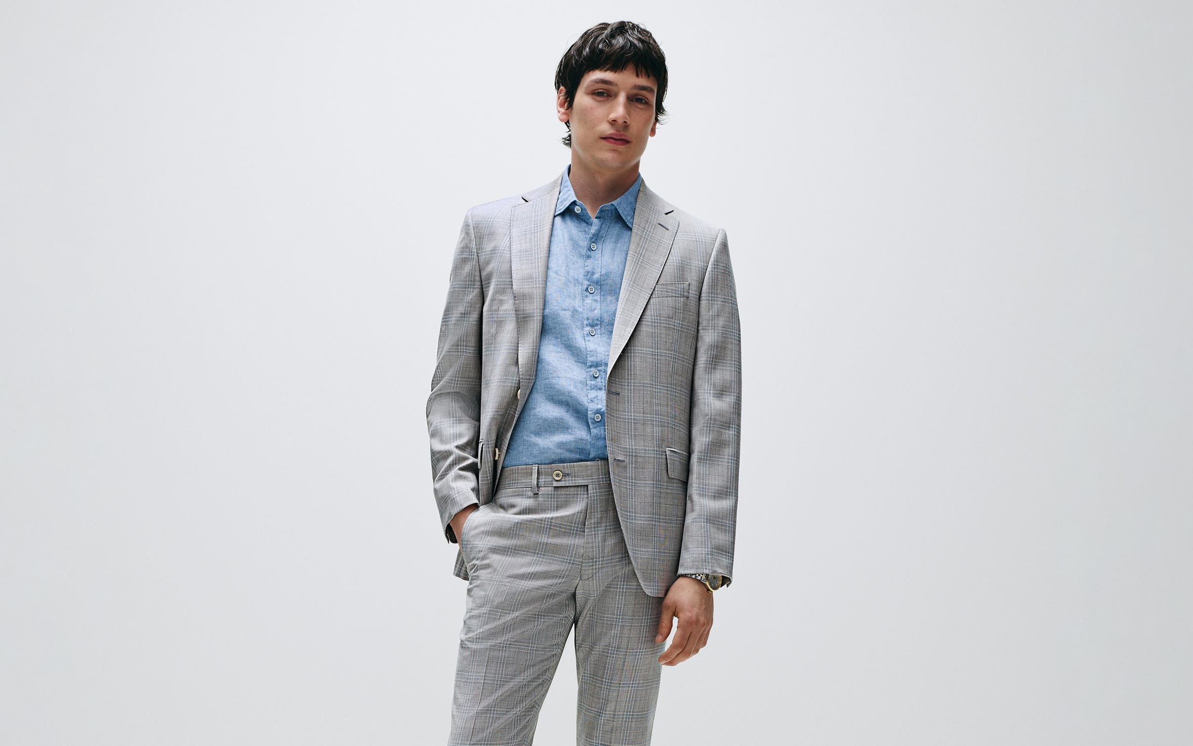 Man wearing a grey plaid suit and blue button-down.