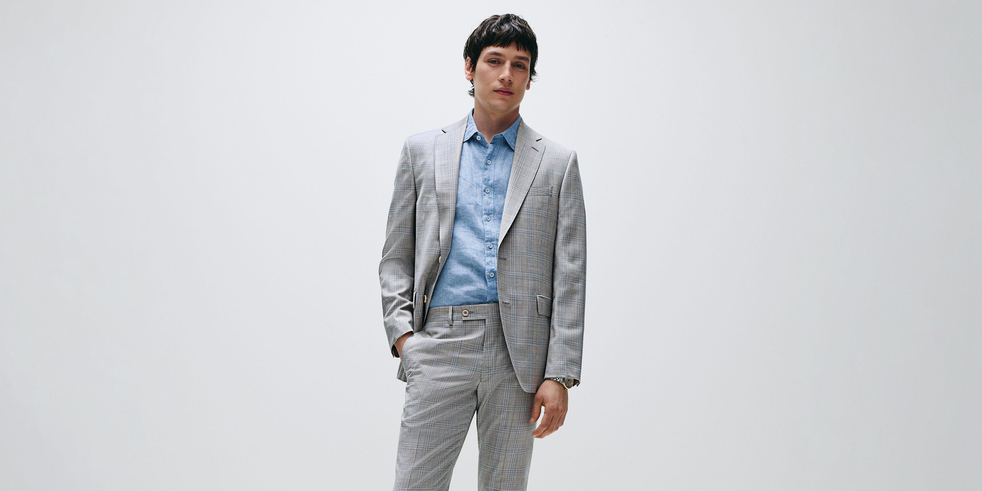 Man wearing a grey plaid suit and blue button-down.