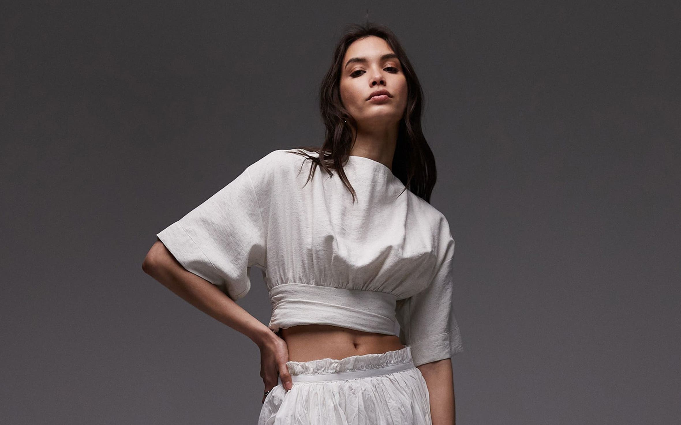 A woman in a white cropped top and flowing white skirt.