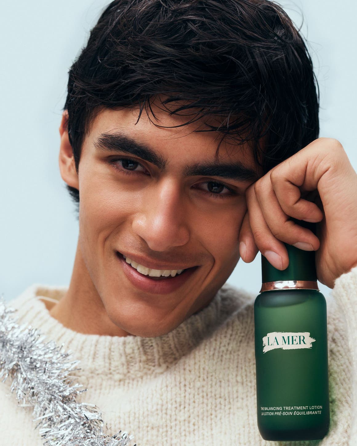 A man holding a La Mer product.  