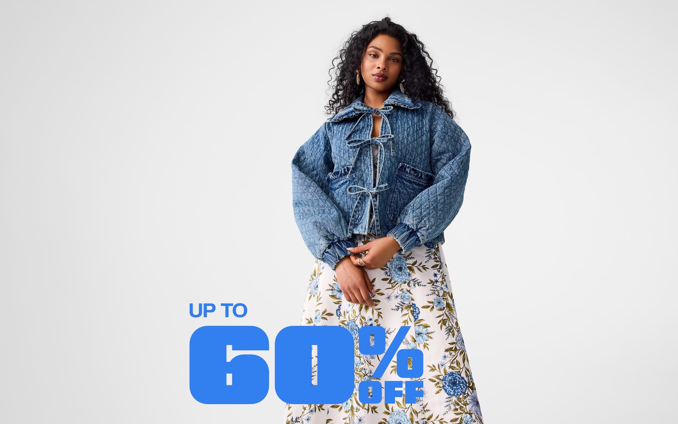 A woman wearing a quilted denim jacket and a floral skirt.