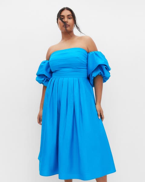 Woman in a bright plus-size strapless dress.