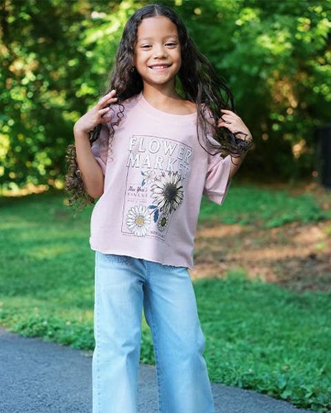 Girl wearing pink Nordstrom graphic tee and jeans.