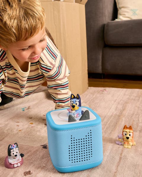Child playing with a Tonies Toniebox audio player and Bluey character figurines