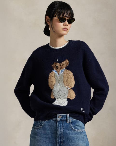 A woman wearing a sweater with an image of a bear.   