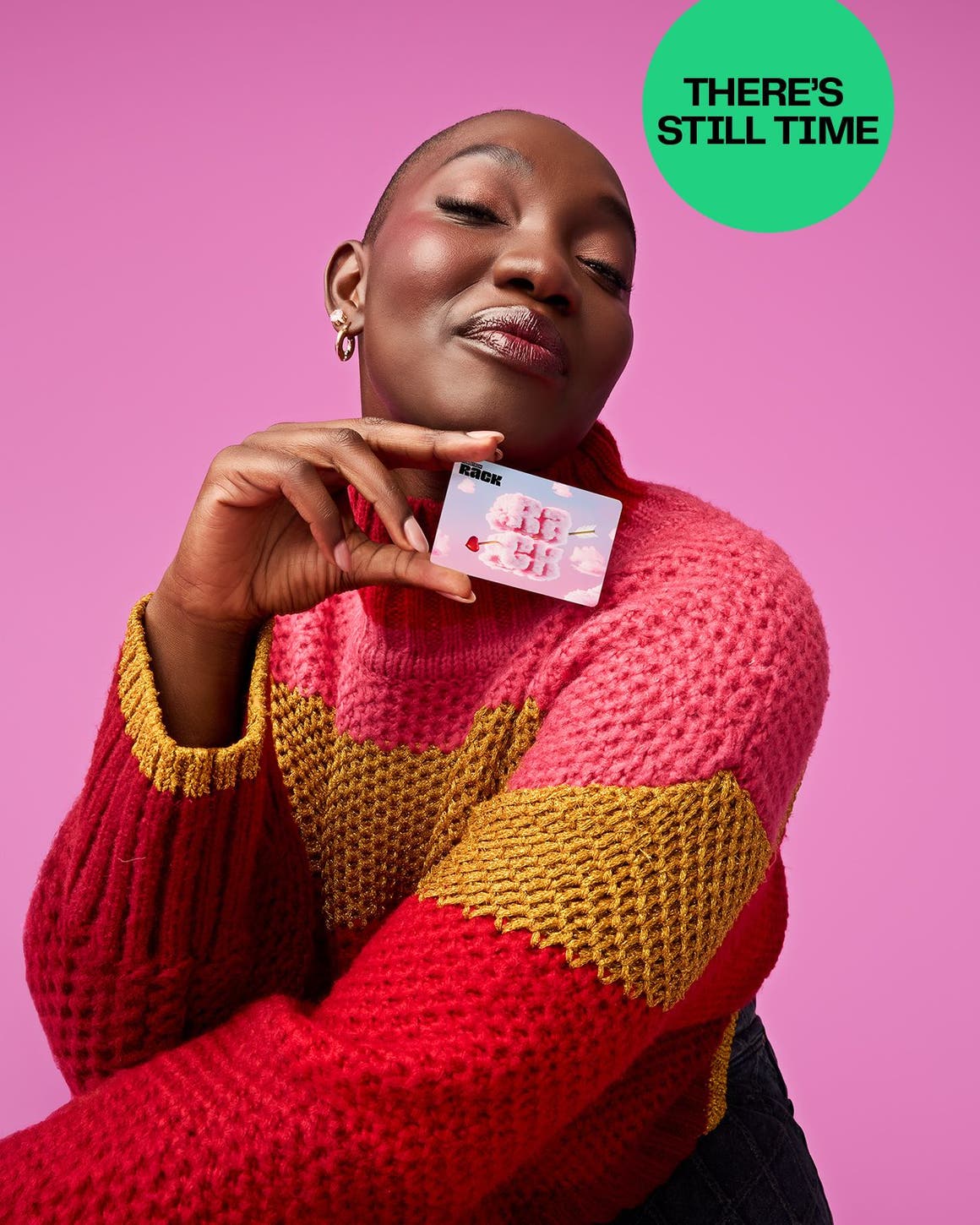 A woman in a pink, yellow and red striped sweater holds up a gift card. 