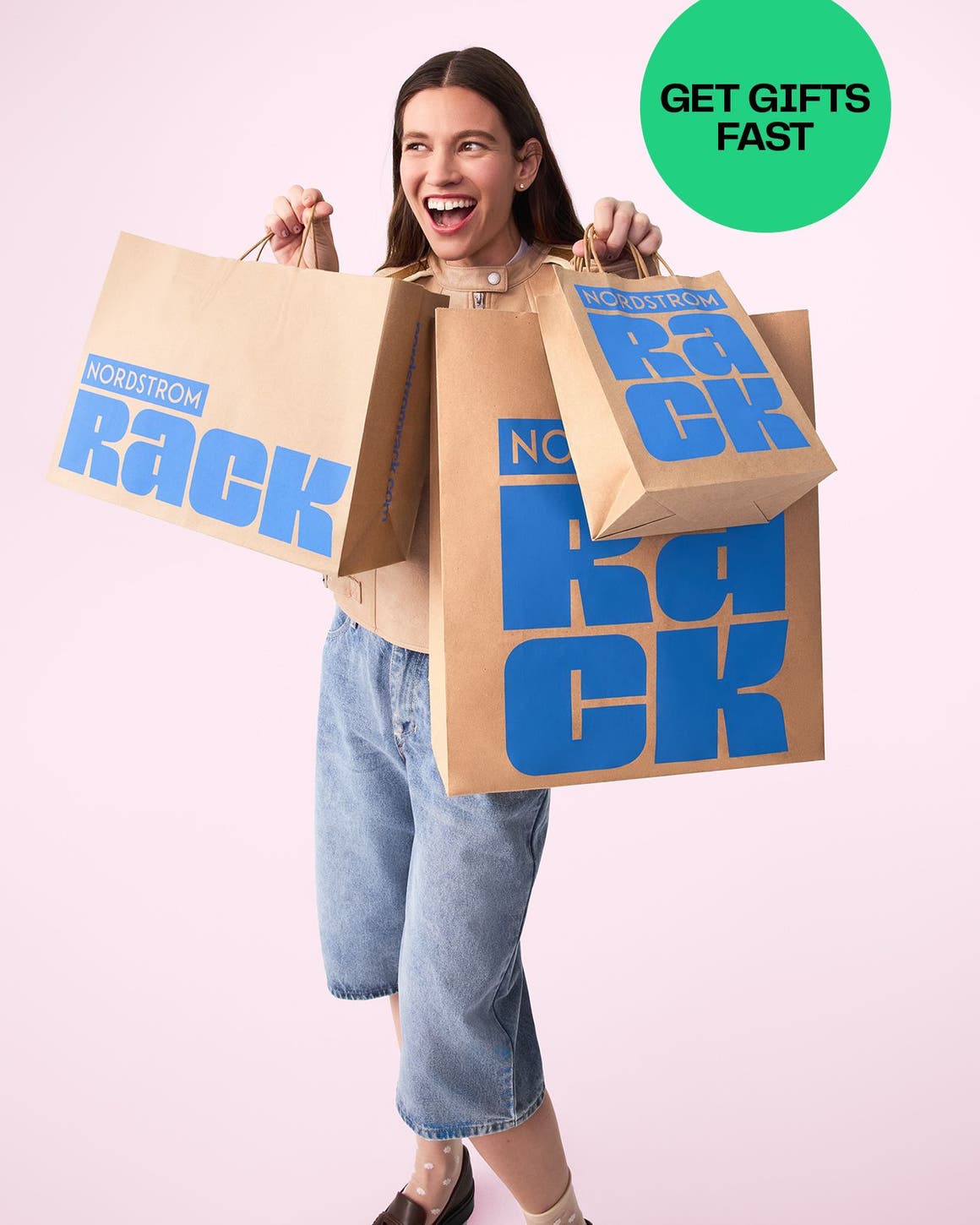 A woman holds 3 Nordstrom Rack shopping bags.