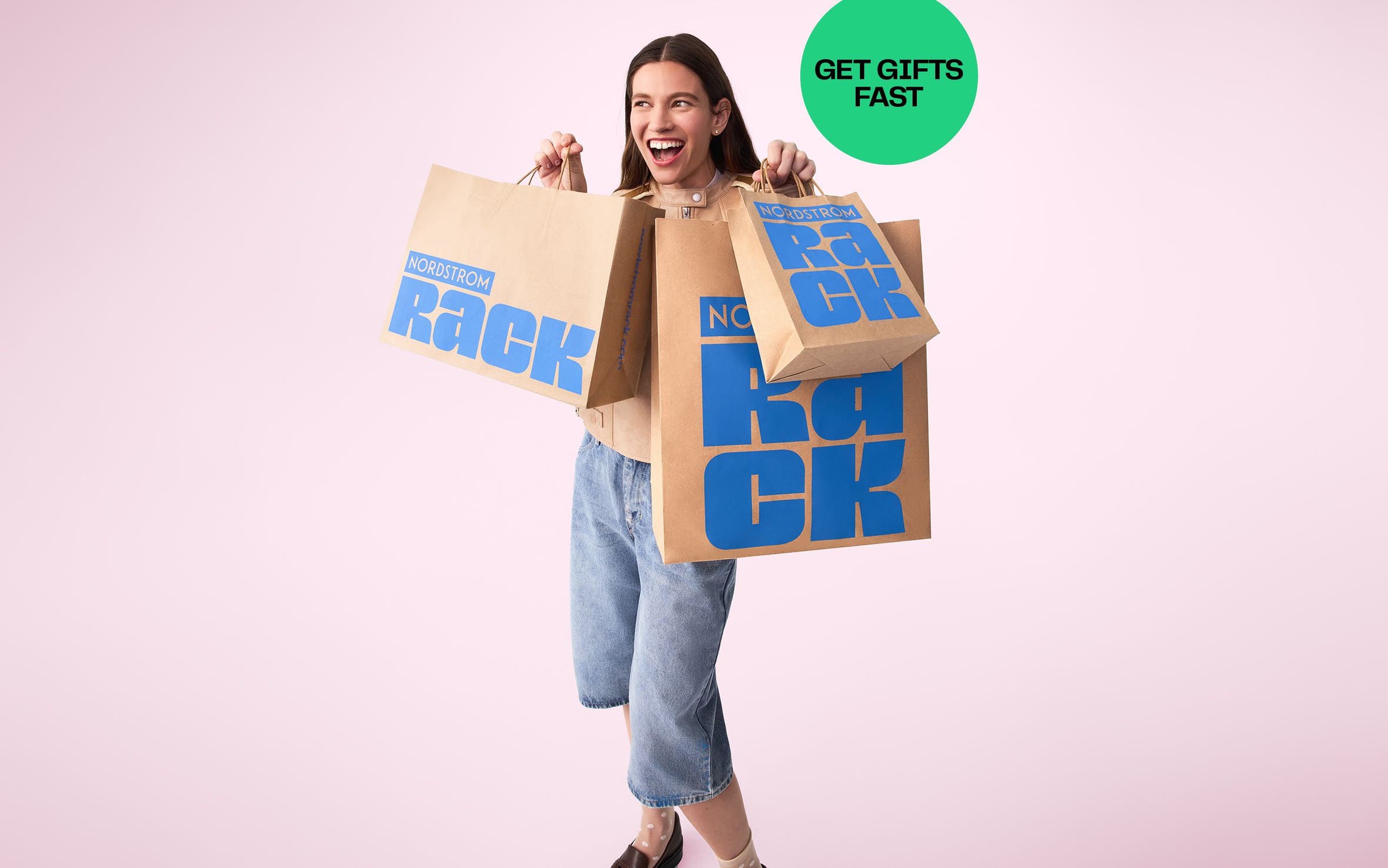 A woman holds 3 Nordstrom Rack shopping bags.