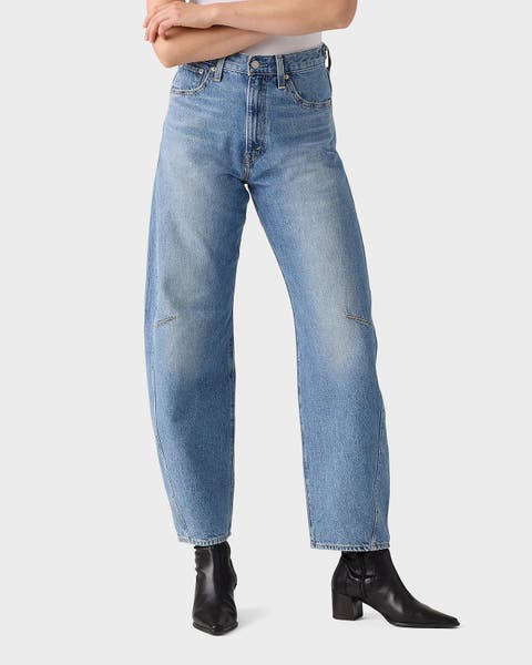 A woman wearing barrel jeans and black boots.