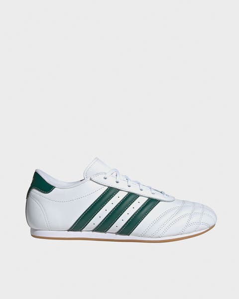 A women’s white sneaker with green stripes.