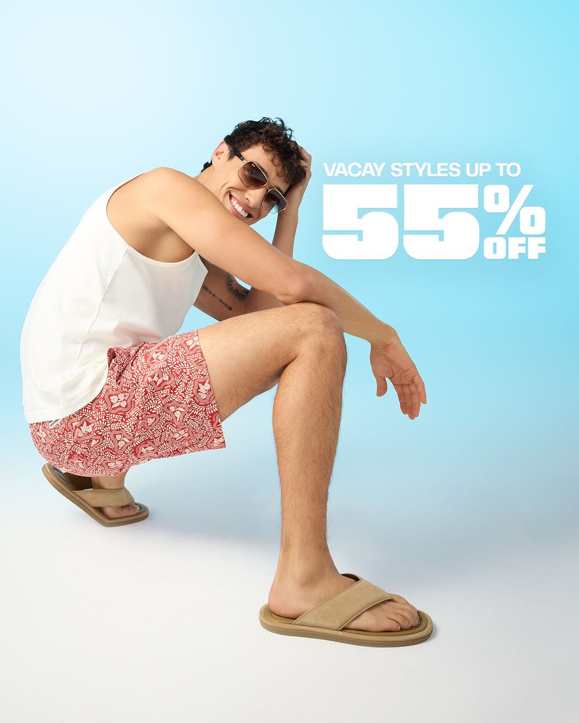 A man wearing a white tank, floral shorts and flip-flops.