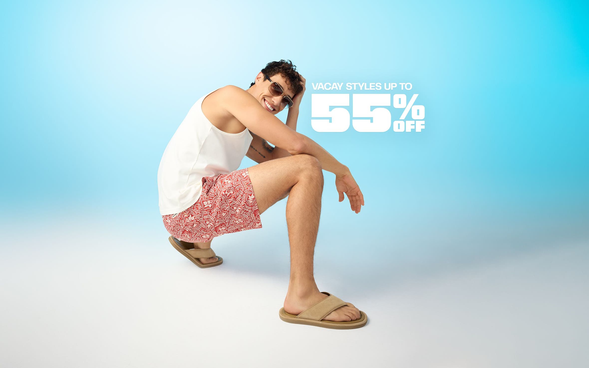 A man wearing a white tank, floral shorts and flip-flops.