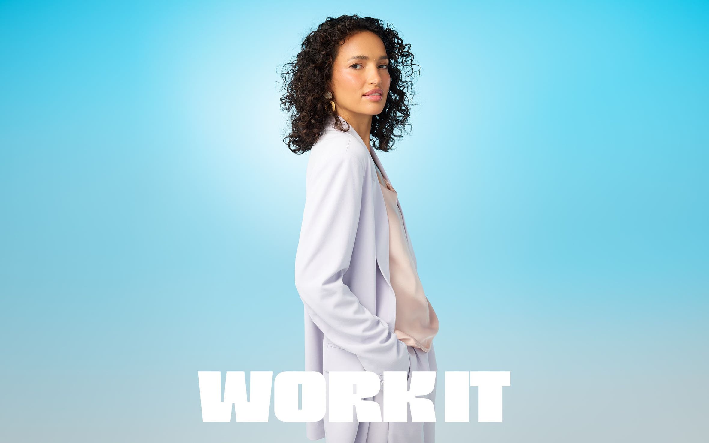 A woman wearing a light peach top and a lavender suit.