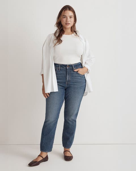 A woman wearing a white tee, button-up shirt, jeans and flats.