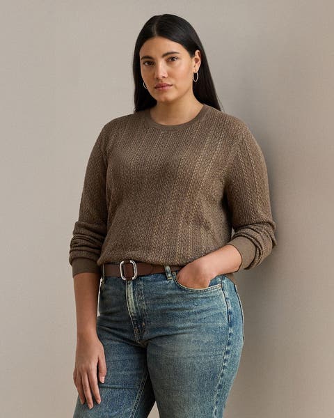 A woman wearing a brown sweater and jeans.