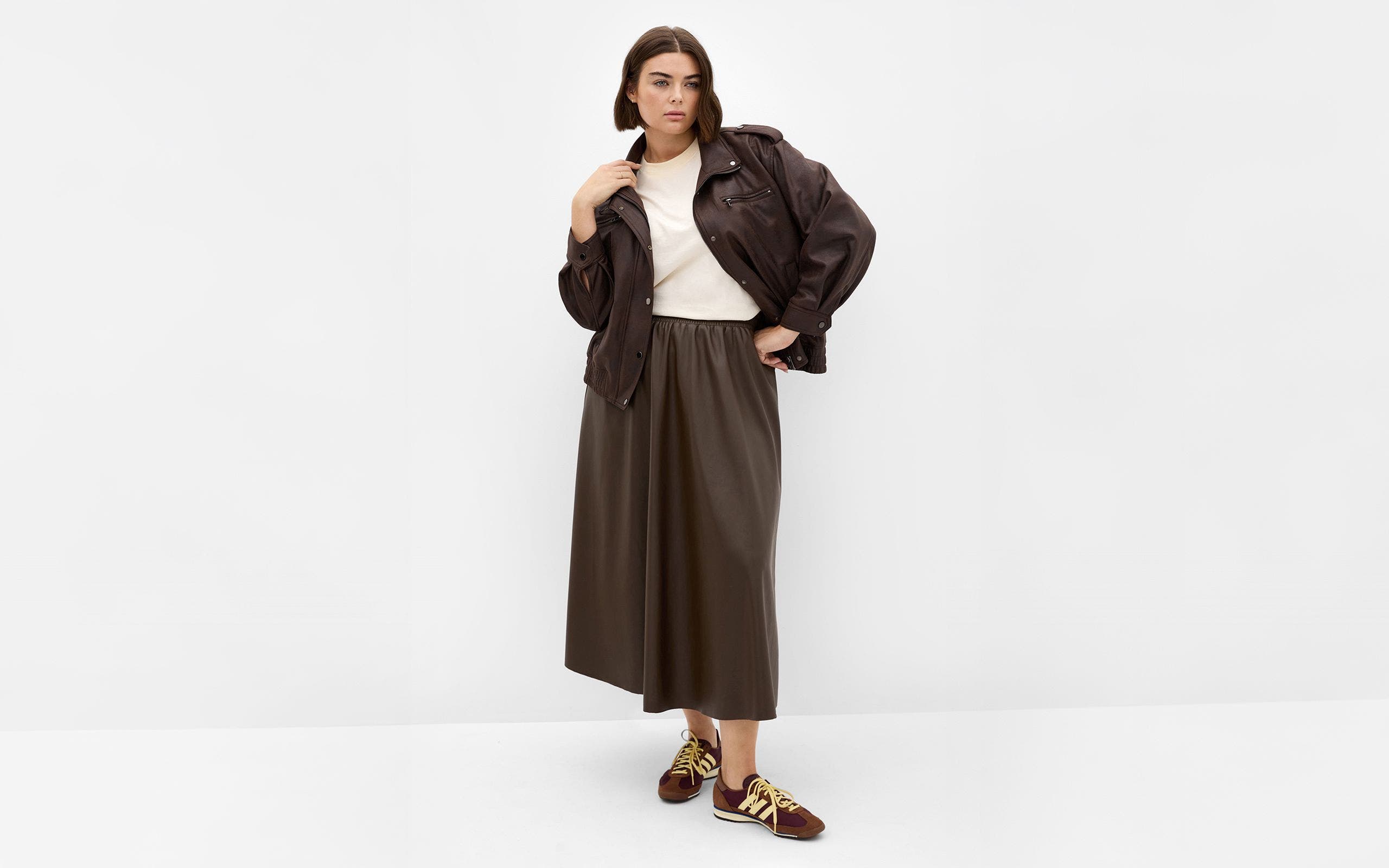 Woman wearing a brown plus-size jacket and white tee.