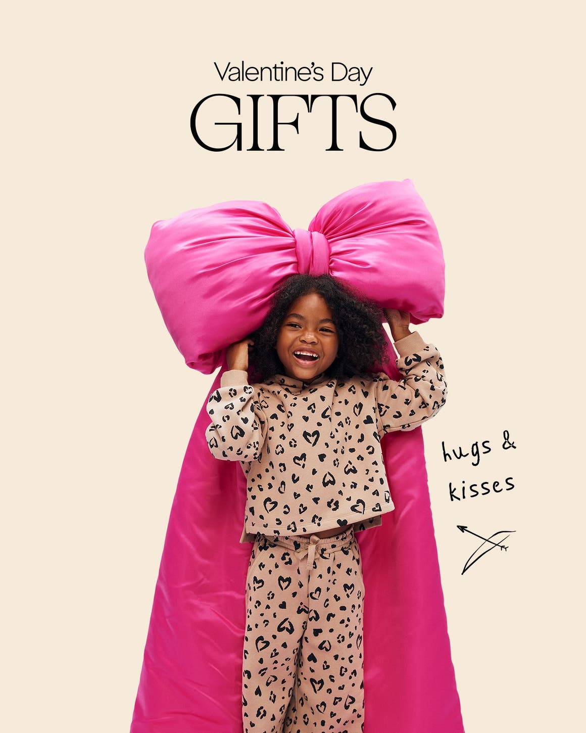 A girl wearing heart-patterned pajamas holding a bow. 