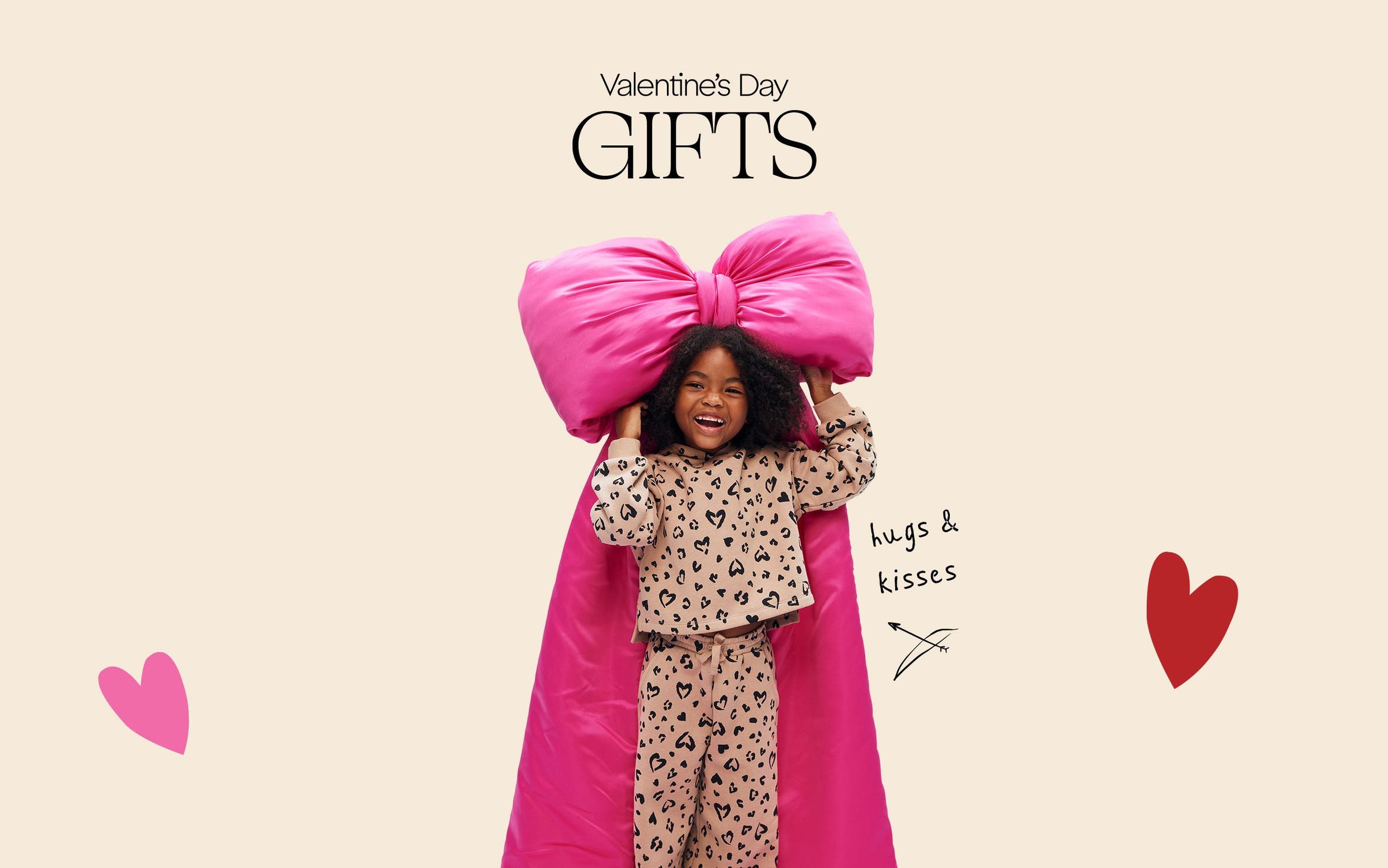 A girl wearing heart-patterned pajamas holding a bow. 