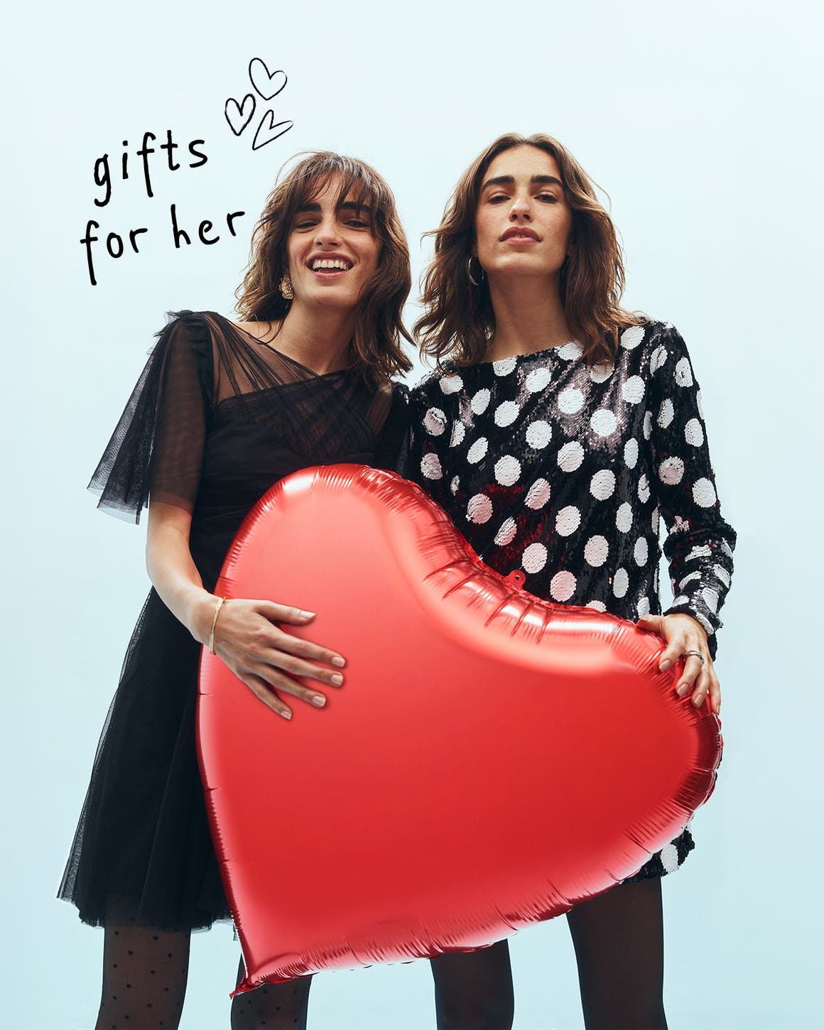Two women holding a heart balloon.