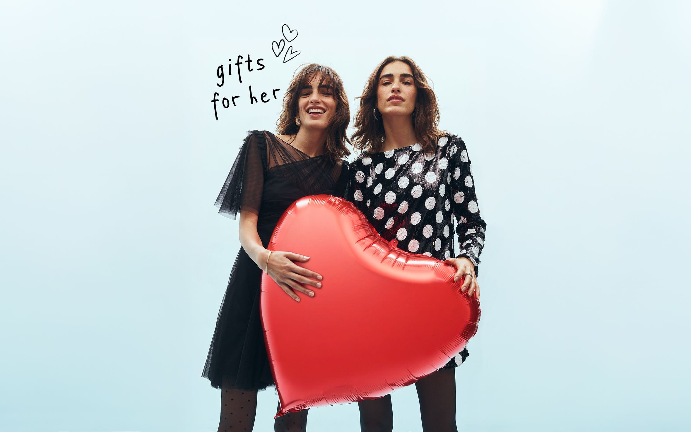 Two women holding a heart balloon.
