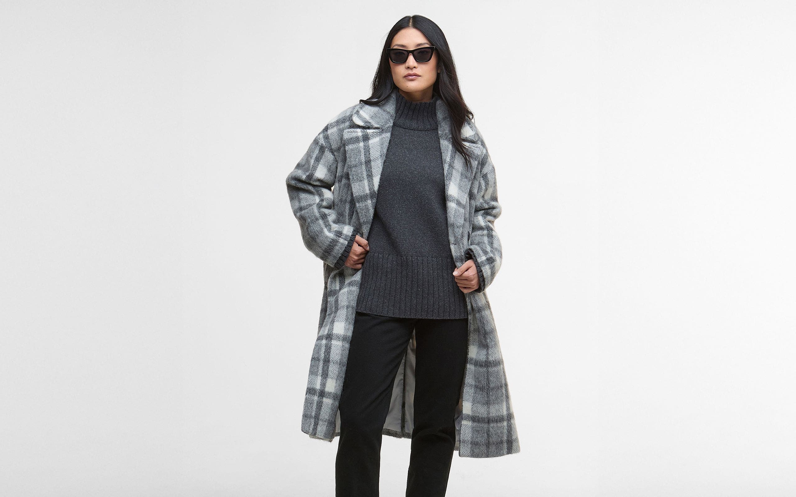 Woman wearing a grey plaid knee length wool coat.
