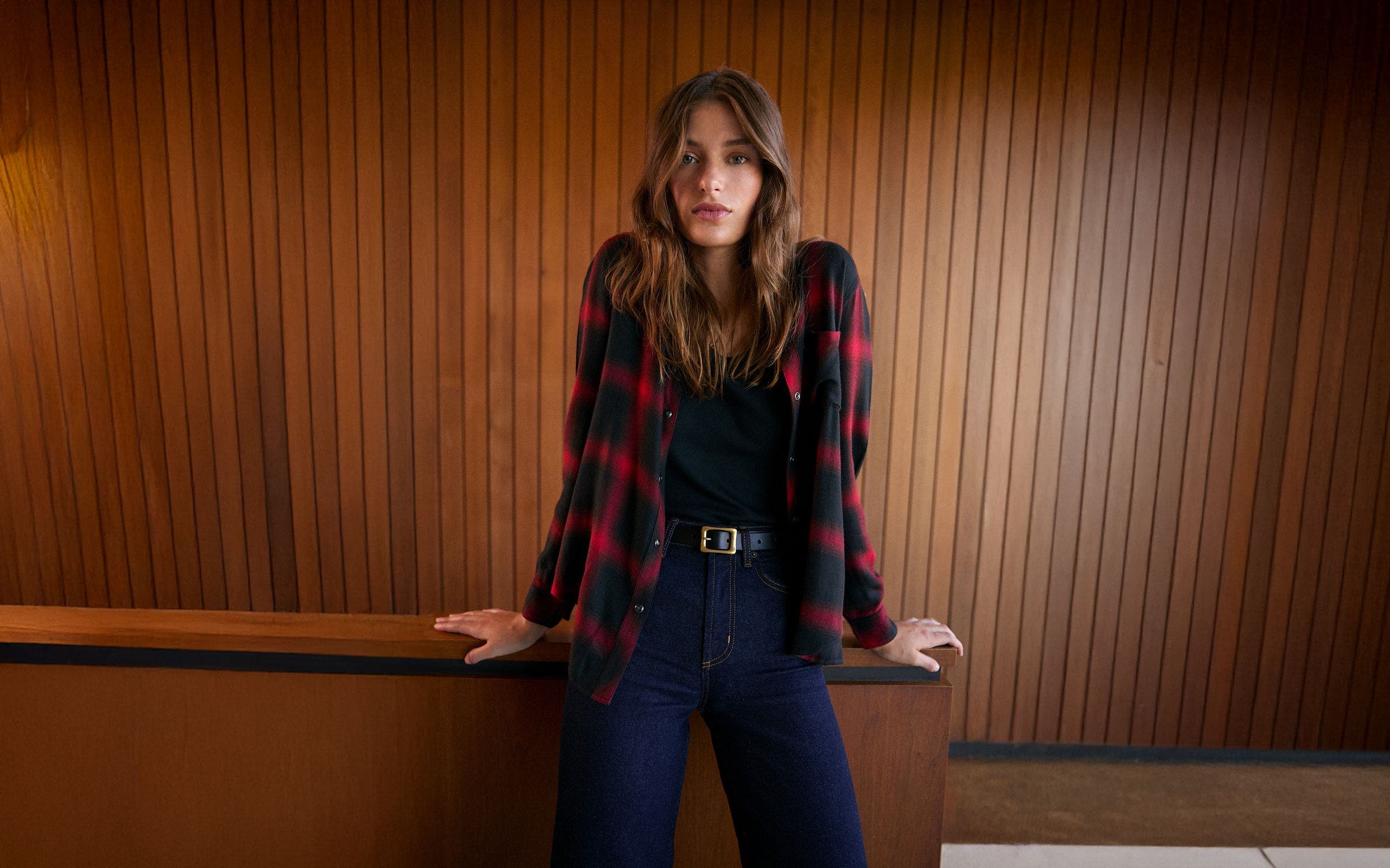 A woman wearing a plaid button-up shirt over a black top.