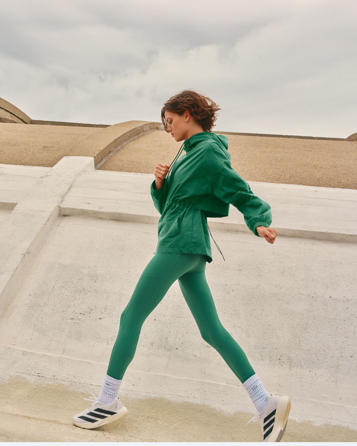 Woman wearing a green active outfit and sneakers.
