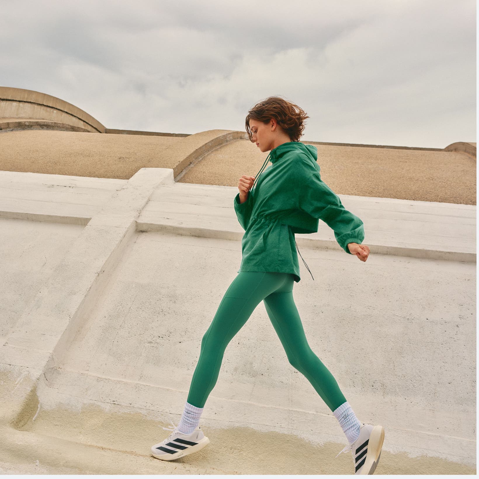Woman wearing a green active outfit and sneakers.