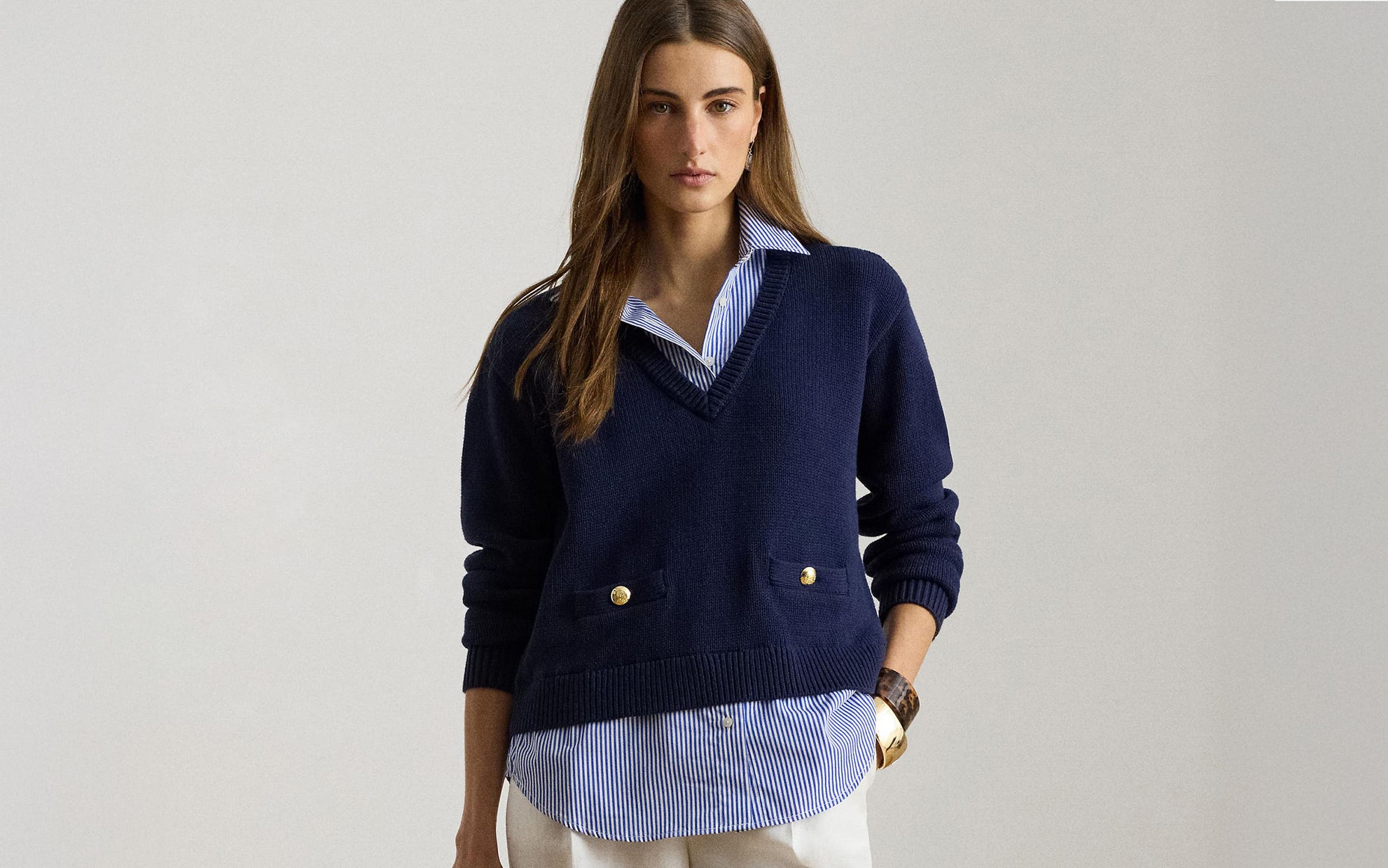 Woman wearing a navy sweater over a blue-and-white striped button-up from Lauren Ralph Lauren.