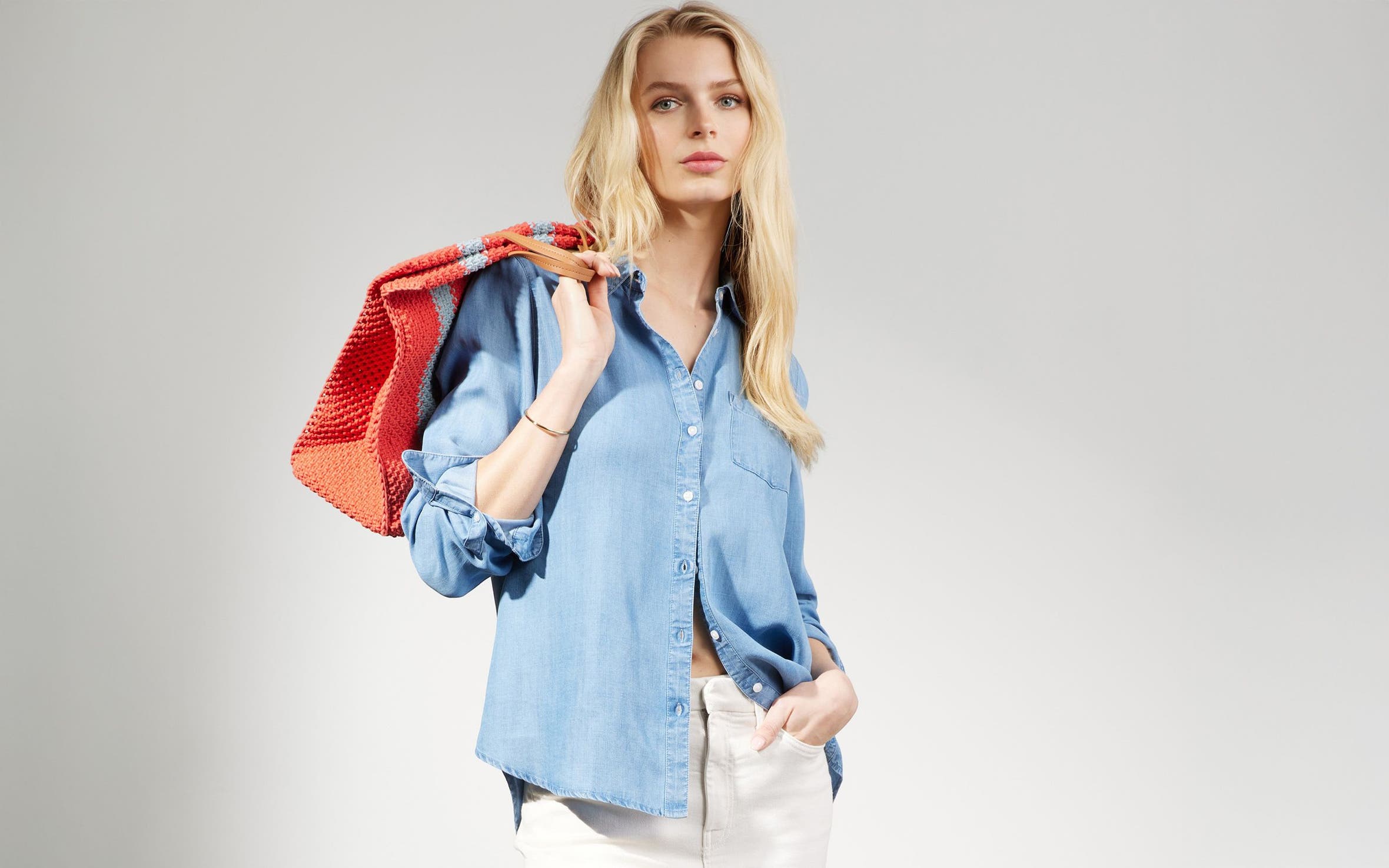 Woman wearing a denim button-up, white jeans and striped tote from Nordstrom Made brands.