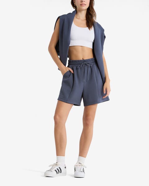 A woman wearing a blue Z by Zella sleeveless vest and matching shorts over a white crop top, with white sneakers.