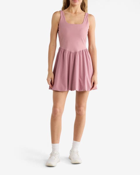 A woman wearing a pink Z by Zella dress with white sneakers.