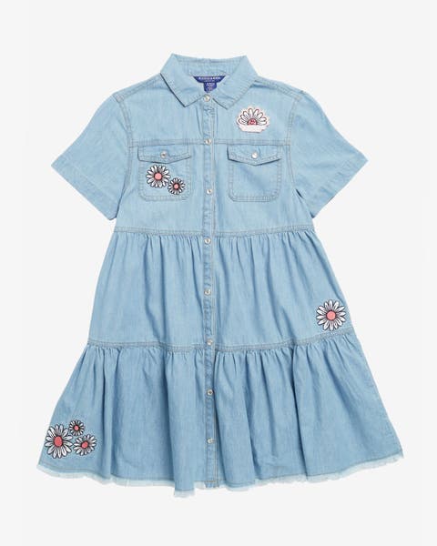 A girls' light denim shirt dress with floral patches.