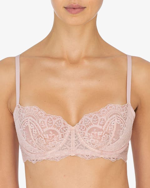 A women wearing a blush pink lace balconette bra with thin straps.