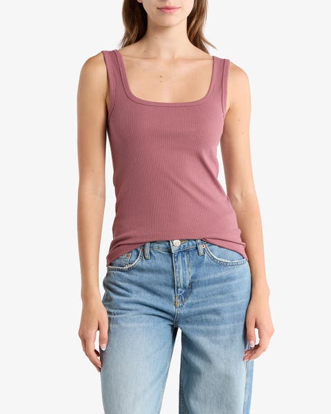 Woman wearing a mauve ribbed tank top, paired with light-wash jeans.
