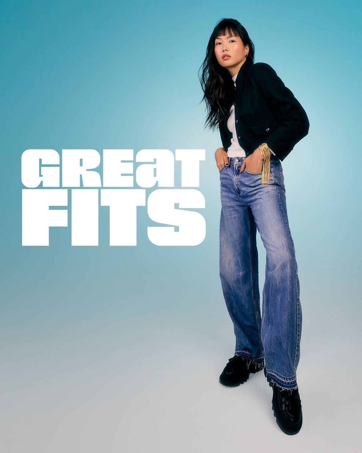 A woman wearing wide-leg light wash jeans and a black cropped jacket.