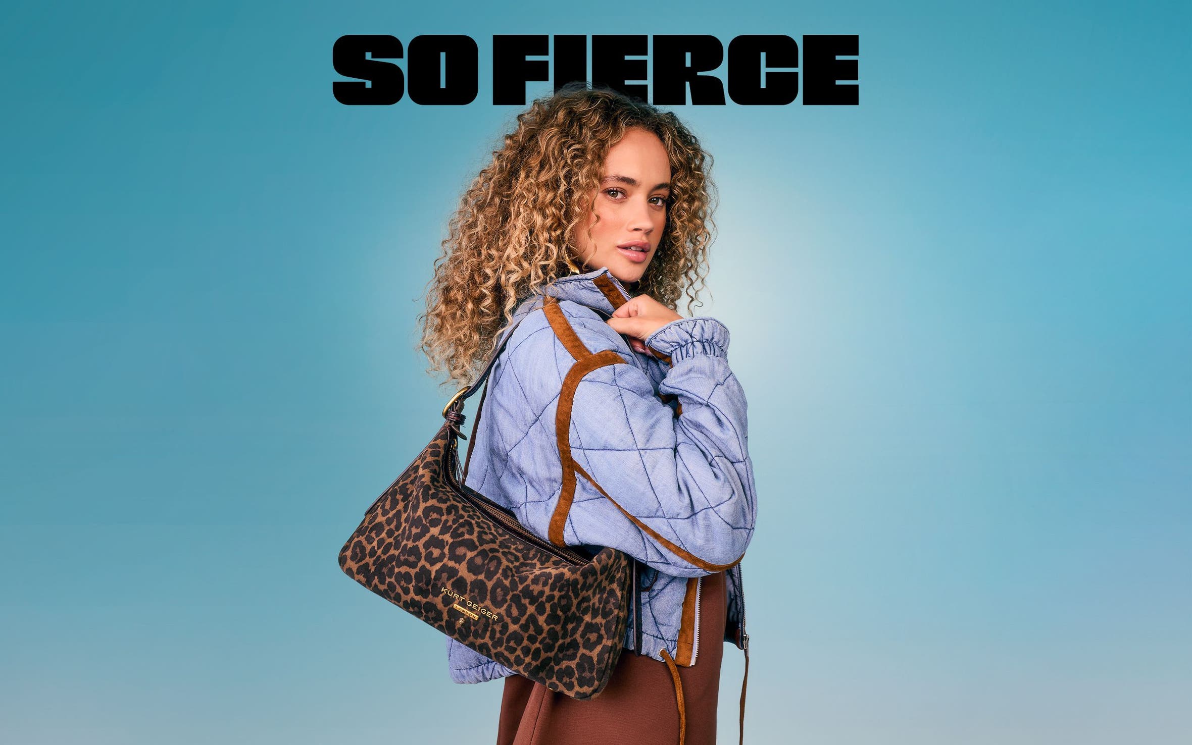 A woman wearing a Kurt Geiger London leopard print shoulder bag and a blue quilted jacket.