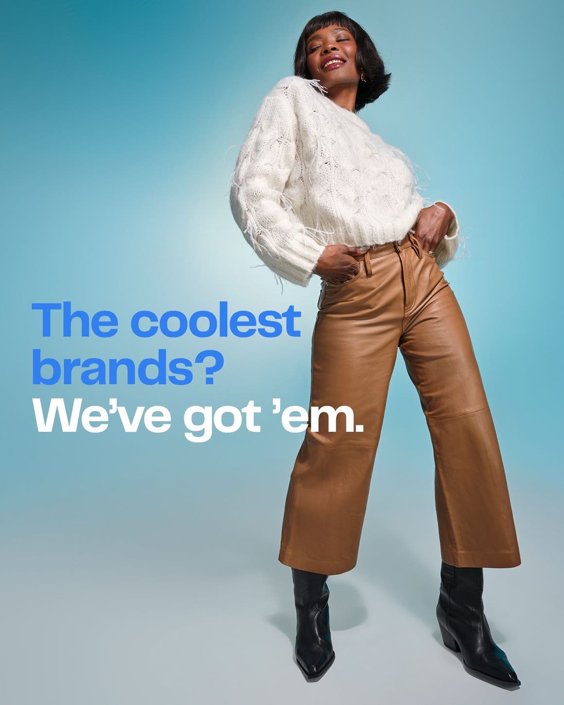 A woman wearing a white sweater, brown pants and black boots.
