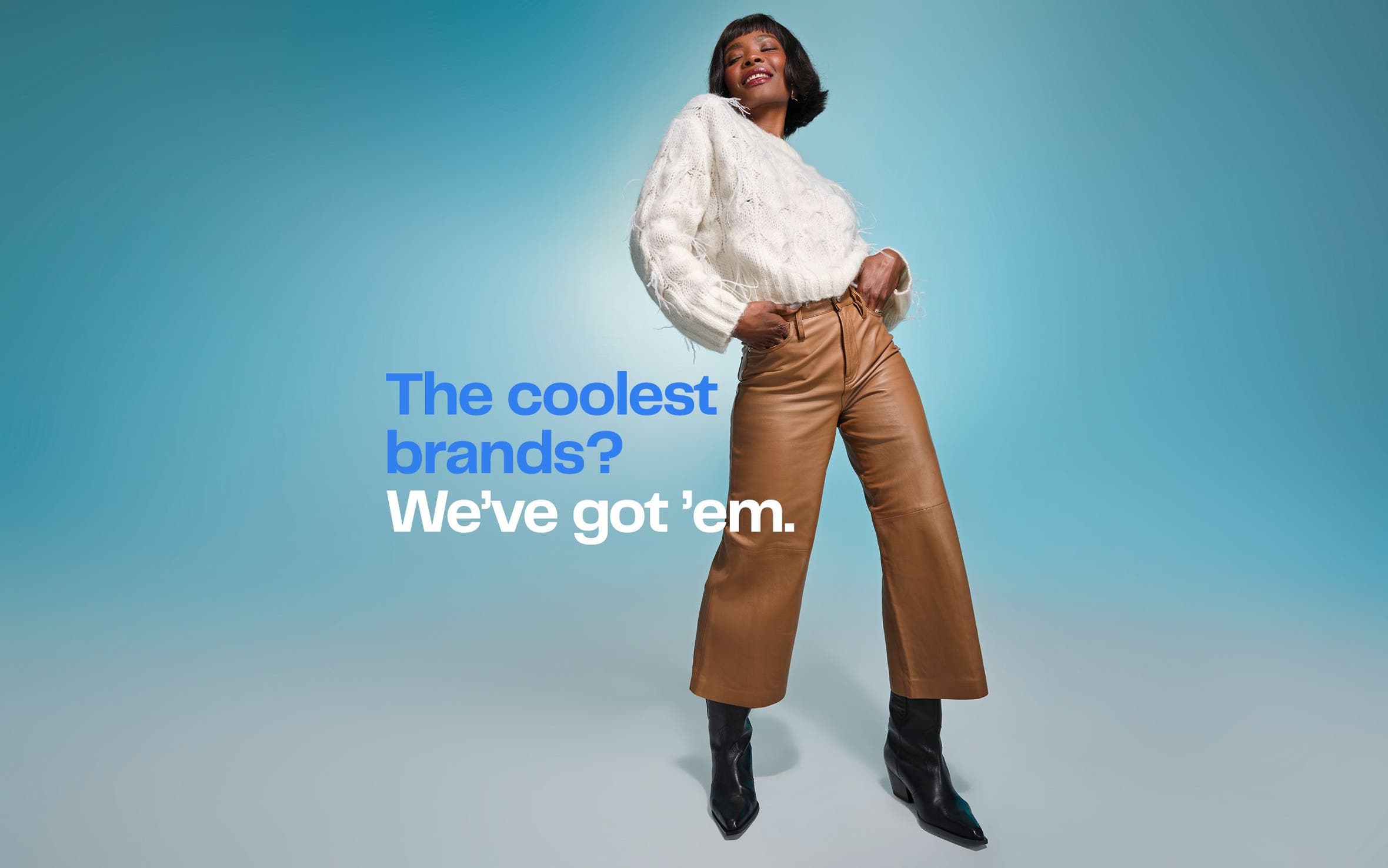 A woman wearing a white sweater, brown pants and black boots.