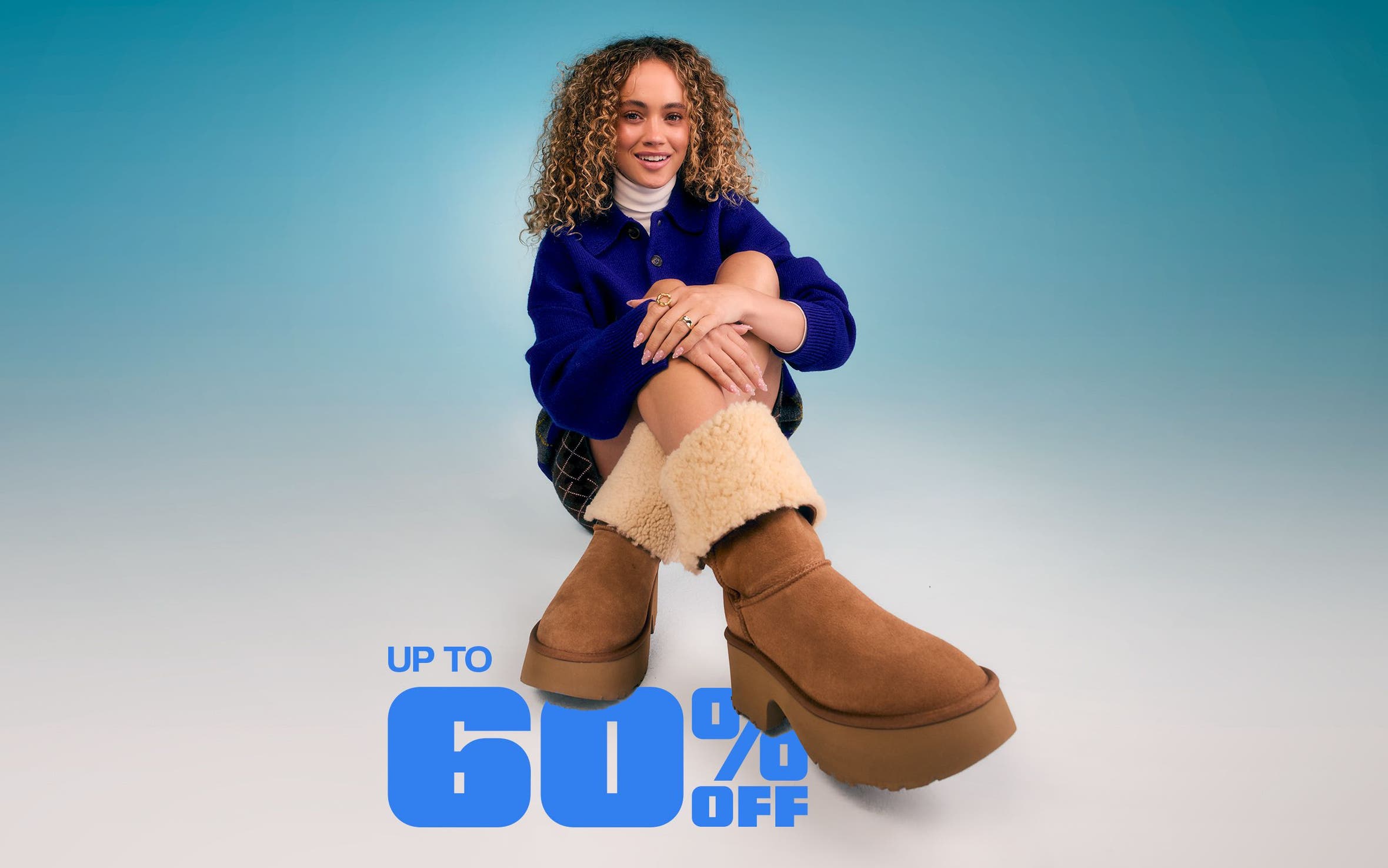 A woman wearing a blue sweater and brown shearling boots.