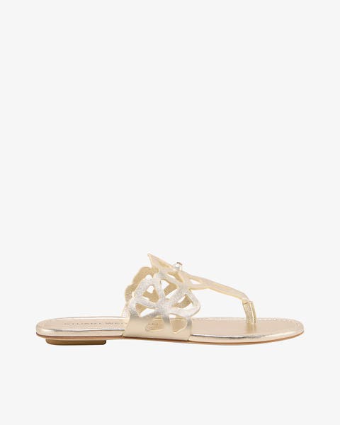 A flat sandal with a decorative cutout medallion on the strap.