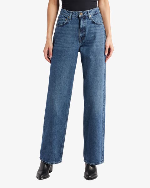 A woman wearing high-waisted jeans and black shoes.