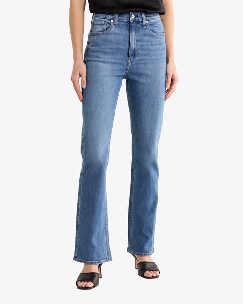 A woman wearing bootcut jeans and black sandals.